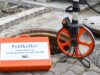 Ein Prüfkoffer vor einem offenen Kanalschacht