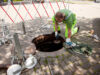 Ein Arbeiter in Warnkleidung kniet neben einem Kanalschacht